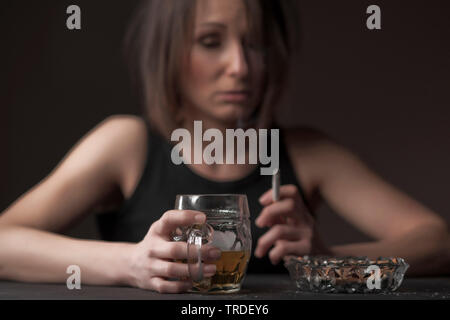 Portrait d'un déprimé et femme désalcoolisée avec un verre de bière et une cigarette dans ses mains Banque D'Images