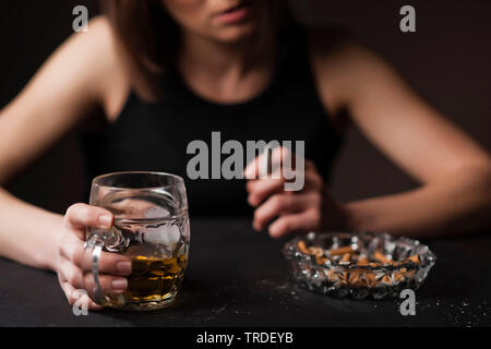 Portrait d'un déprimé et femme désalcoolisée avec un verre de bière et une cigarette dans ses mains Banque D'Images