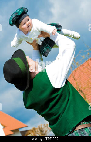 Portrait d'un jeune homme habillé en costume traditionnel tenant un bébé, l'Allemagne, la Bavière Banque D'Images