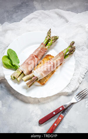 Jeunes frais enveloppé dans le Prosciutto Asperges viande sur une table béton rustique. Banque D'Images