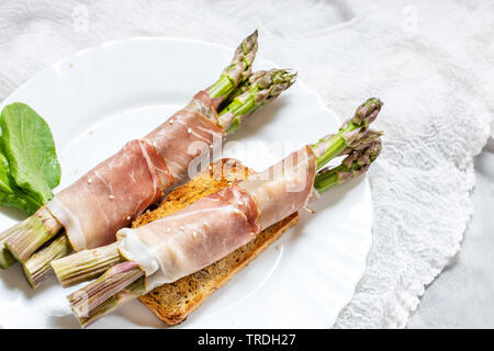 Jeunes frais enveloppé dans le Prosciutto Asperges viande sur une table béton rustique. Banque D'Images