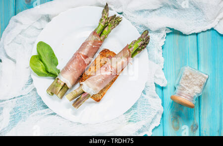 Jeunes frais enveloppé dans le Prosciutto Asperges viande sur une table en bois bleu. Banque D'Images