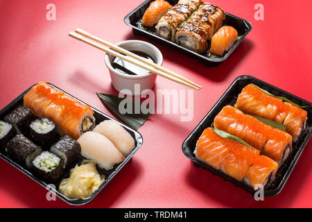 Différents types de rouleaux de sushi servi sur fond rouge Banque D'Images
