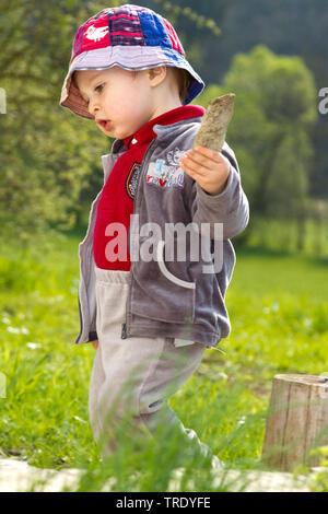 Portrait d'un jeune garçon jouant sur la pelouse avec un morceau de bois Banque D'Images