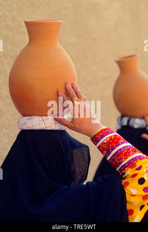 L'équilibrage des femmes voilées à l'argile sur la tête, Emirats Arabes Unis, Dubai Banque D'Images