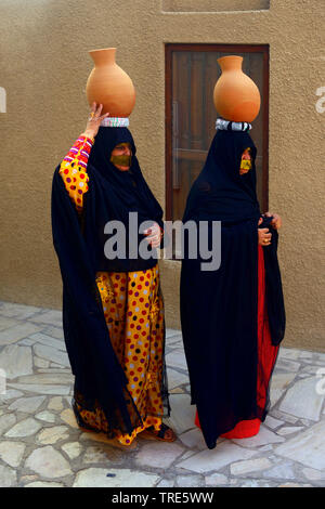 L'équilibrage des femmes voilées à l'argile sur la tête, Emirats Arabes Unis, Dubai Banque D'Images
