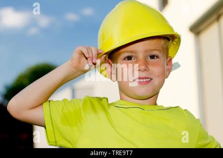 Portrait de mi-longueur d'un jeune garçon tenant une trop grande casque avec sa main Banque D'Images