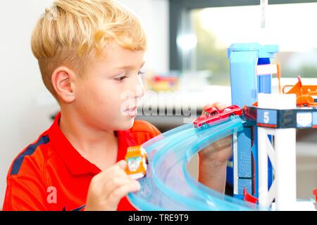 Jeune garçon jouant avec des voitures dans un garage de stationnement de jouets Banque D'Images