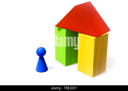 Un pion bleu en face d'un jouet maison construite en bois briques Banque D'Images