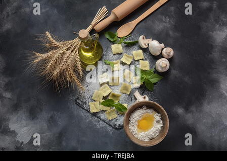 Raviolis aux champignons crus italiens, le basilic, la farine, le blé, l'huile d'olive sur fond sombre.Chavouot juive de food concept Banque D'Images