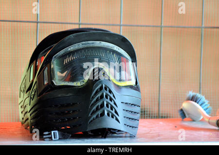 L'équipement de Paintball. Un casque de protection, avec un masque pour protéger le visage, prêt à être porté à la bataille. À côté de la brosse pour enlever la peinture res Banque D'Images