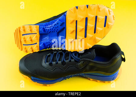 Espadrille noire avec incrustation orange, maille, sur un fond jaune, l'exécution et de remise en forme sneakers sur fond jaune Banque D'Images