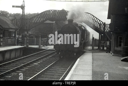 1950, historique, un train à vapeur entrant dans la gare, du village de Chiworth, près de Guildford, Surrey, Angleterre, ROYAUME-UNI. Le numéro à l'avant de la locomotive à vapeur du chemin de fer britannique est 31796. La gare a commencé ses activités en 1849 et était à l'origine connue sous le nom de Chilworth et Albury, incorporant le village voisin d'Albury. À ce moment-là, la vieille passerelle historique et les portes de passage étaient toujours en service. Banque D'Images