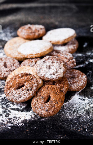 L'avoine et aux pépites de chocolat cookies frais avec du sucre en poudre heap sur fond noir. Banque D'Images