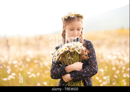 Smiling teen girl 14-16 ans holding Flowers standing in meadow. Le printemps. Banque D'Images