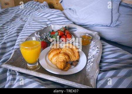 Délicieux petit-déjeuner français le bac est sur le lit. les fraises et des croissants pour le petit déjeuner Banque D'Images