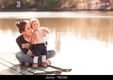 Smiling mother holding baby girl à l'extérieur. Portant des pulls. Saison d'automne. Banque D'Images