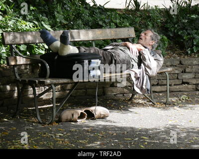 Homme âgé de dormir sur un banc de parc sur un matin ensoleillé en juin Banque D'Images