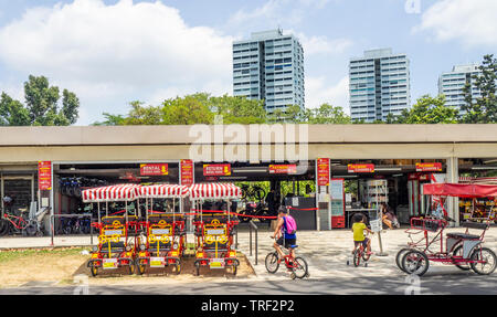 Les garçons la bicyclette avec des roues de formation en face de la location de vélos depot le long de East Coast Park Singapour. Banque D'Images