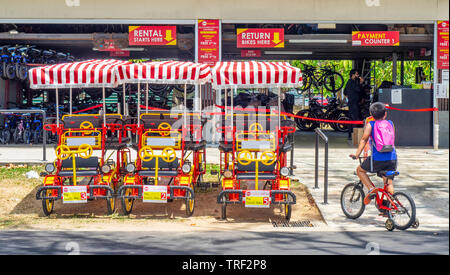 Boy riding a bicycle avec roues de formation en face de la location de vélos depot le long de East Coast Park Singapour. Banque D'Images