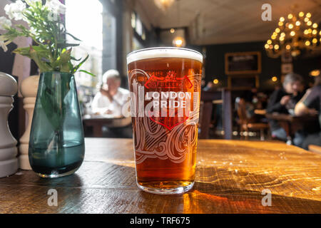 Une pinte de Fuller's London Pride bière sur une table en bois dans un pub Banque D'Images