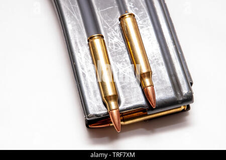 Un fusil de calibre 223 metal magazine chargé avec des balles de calibre 223 avec deux balles dessus isolé sur fond blanc Banque D'Images