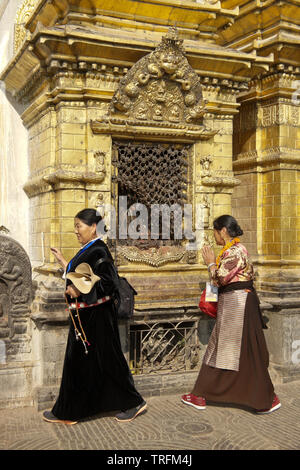 Les femmes en costume traditionnel tibétain à adorer une niche dorée du grand stupa de Swayambhunath temple bouddhiste, Katmandou, Vallée de Katmandou, NEP Banque D'Images