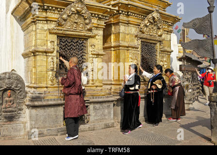 Pèlerins tibétains en costume traditionnel d'offices de la grande niches dorées au temple bouddhiste de Swayambhunath Stupa, Katmandou, la vallée de Katmandou, N Banque D'Images