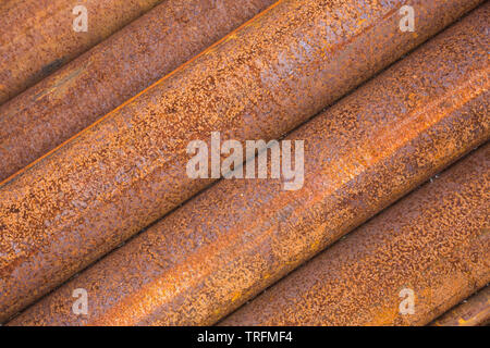 Close-up en angle vue de côté le marron et l'orange longueur de l'acier rouillé des pipes tubulaires empilées dans un tas à Didcot Railway Centre, Oxfordshire, UK. Banque D'Images