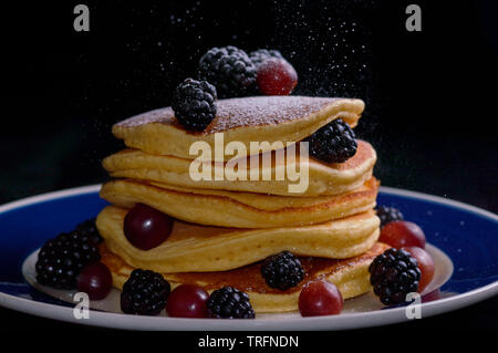 Des crêpes empilées avec de petits fruits d'été et la baisse de sucre glace , isolé sur noir. La nourriture, le petit déjeuner, collation. Copie espace#  Banque D'Images