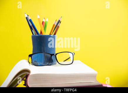 Crayons de couleur dans une trousse et verres sur un fond jaune library concept éducation retour à l'école / Crayon Banque D'Images