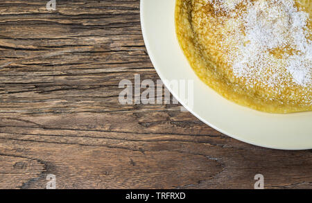 Crêpe mince avec du sucre sur fond de bois. Mise à plat. Banque D'Images