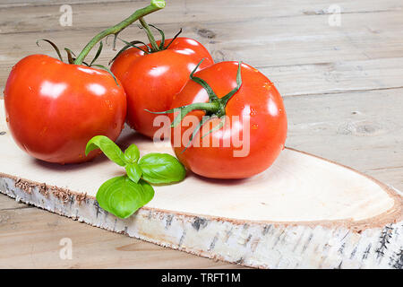 Tomates rouges mûres et de feuilles de basilic frais sur le bois. Banque D'Images
