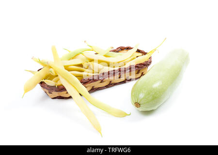 Panier en bois jaune avec les jeunes gousses de fèves et haricots rouges et courgette verte avec de l'eau gouttes isolé sur fond blanc Banque D'Images