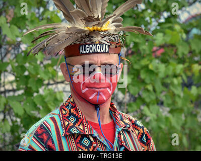 Algonquin Canada/Premières Nations Iroquoises homme avec un visage peint porte ses warbonnet et pose pour la caméra lors d'un pow-wow. Banque D'Images