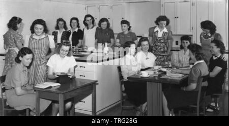 Années 1950, historique, un groupe de jeunes filles, certains portant des pinafores et tabliers, dans une classe dans un collège technique, England, UK. Banque D'Images