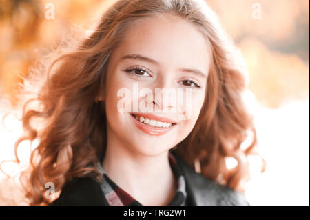 Closeup portrait of teenage girl automne 13-14 ans smiling over feuilles jaunes à l'extérieur. En regardant la caméra. Banque D'Images