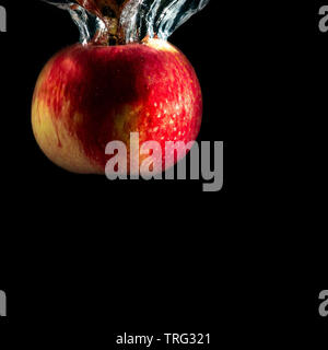 Pomme mûre rouge tombe dans l'eau avec des touches Banque D'Images