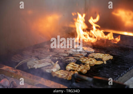 Un assortiment de grillades brochettes de viande de poulet, d'agneau et de porc mariné kofte, saucisses et légumes divers griller sur la grille du barbecue cuit Banque D'Images