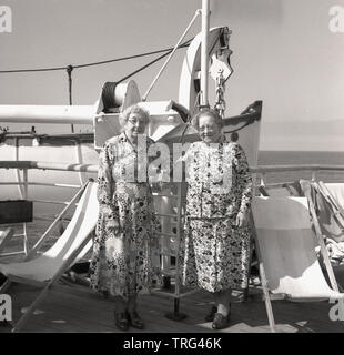 Années 1950, historiques, une croisière sur un paquebot en cette époque, deux dames âgées portant des robes à motifs de fleurs à l'extérieur sur le pont de la P & O Chusan bateau de croisière. Banque D'Images