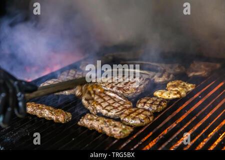 Vue de dessus du boeuf rôti mixte quatre brochettes, sur BBQ Charcoal Grill chaud et dynamique des flammes de feu isolé sur fond noir. Concept pour Été Part Banque D'Images