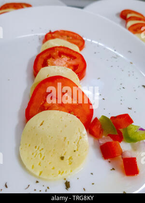 Roues de tomate et de fromage sur une plaque blanche Banque D'Images