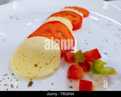 Roues de tomate et de fromage sur une plaque blanche Banque D'Images