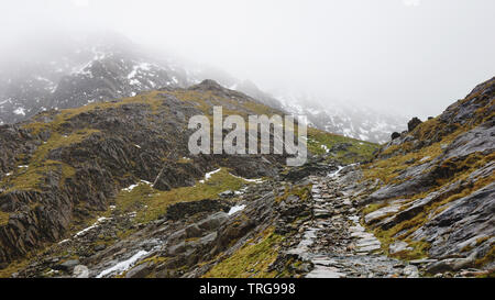 Paysage magnifique avec un ciel brumeux, la fonte des glaces et de la route entre les belles montagnes escarpées - capturés au cours d'une randonnée à Snowdon en hiver (Na Snowdonia Banque D'Images