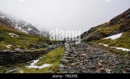 Paysage magnifique avec un ciel brumeux, la fonte des glaces et de la route entre les belles montagnes escarpées - capturés au cours d'une randonnée à Snowdon en hiver (Na Snowdonia Banque D'Images