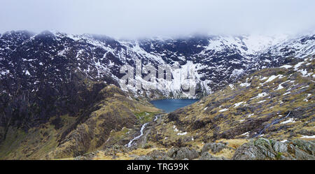 Vue imprenable sur la montagne avec du brouillard, du lac et des cours d'eau avec la fonte des neiges - capturés au cours d'une randonnée à Snowdon en hiver (Parc National de Snowdonia, W Banque D'Images