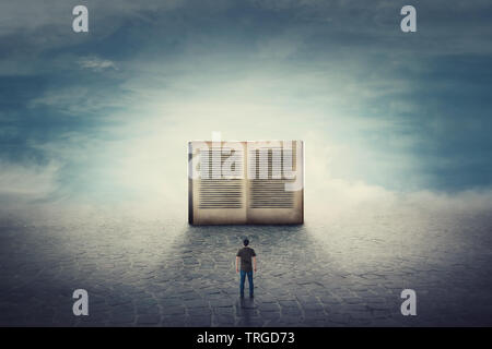 Scène surréaliste comme guy étudiant se dresse sur un trottoir en face de la route d'un gigantesque livre ouvert. L'importance de la lecture et de la littérature dans le monde moderne. Banque D'Images