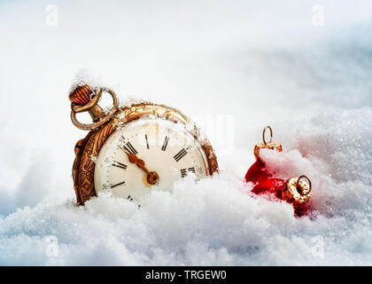 Nouvelle année réveil avant minuit. Montre de poche antique et boules de Noël rouge dans la neige. Concept de vacances Banque D'Images