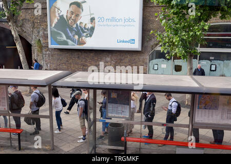 Sous un panneau d'annonce en ligne pour le site web d'emploi LinkedIn une file de passagers d'un bus à attendre le prochain service à la gare de Waterloo au cours de l'heure de pointe du matin, le 5 juin 2019, à Londres, en Angleterre. Banque D'Images