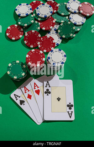 Quatre as et des jetons de poker, sur la surface verte, avec la lumière du soleil de l'après-midi Banque D'Images